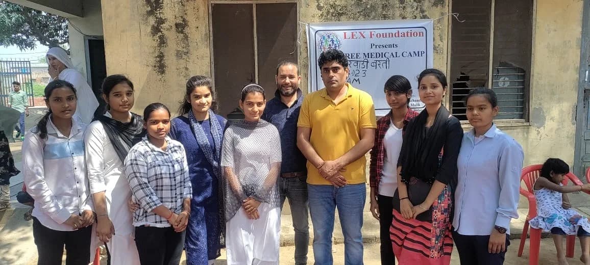 A group of young women posing together outside a venue hosting a free medical camp.